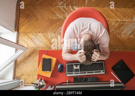 L'homme travaille à distance à la maison sur un ordinateur et il subit le stress. Concept d'auto-isolation pendant une pandémie. Style de vie moderne. Banque D'Images