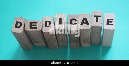 Mot dédié sur une rangée de blocs de bois. Concept d'amour de dévouement Banque D'Images