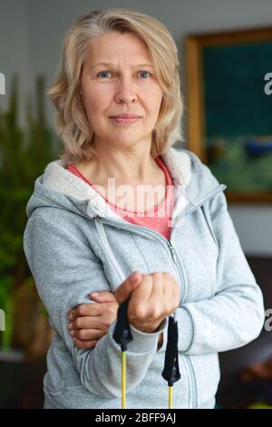 Rester en forme est une façon de vieillir avec grâce. Belle femme âgée prenant plaisir à l'entraînement. Femme active senior à la maison s'exerçant avec des poids. Matu Banque D'Images