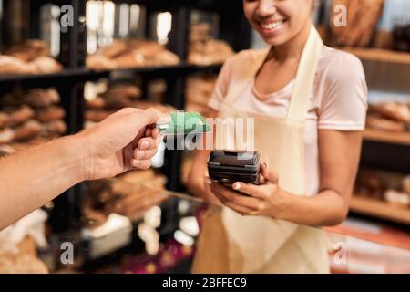 Jeune femme adulte travaillant dans une petite boulangerie avec un client Banque D'Images