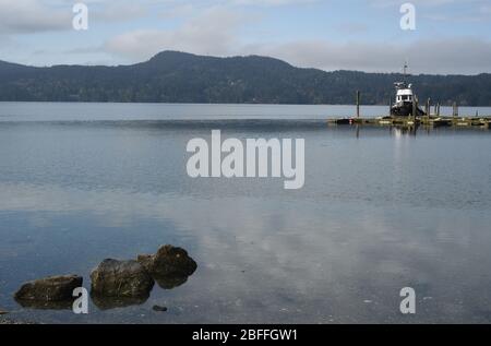 Un bateau est attaché à un quai dans les eaux du bassin de Sooke, un matin ensoleillé du printemps d'avril à Sooke, sur l'île de Vancouver, en Colombie-Britannique, au Canada Banque D'Images