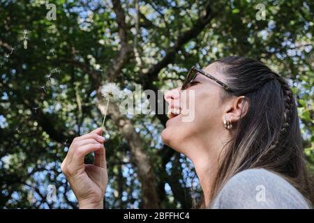 un beau modèle de femme jouant avec un pissenlit dans le bois Banque D'Images