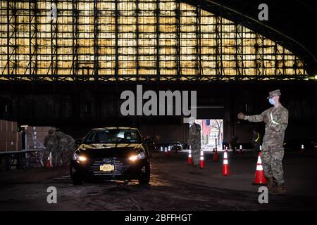 Bronx, États-Unis d'Amérique . 18 avril 2020. Un soldat de l'armée américaine instruit un chauffeur de taxi à l'Armory de Kingsbridge dans le Bronx le 18 avril 2020. L'armory est utilisé comme centre temporaire de distribution alimentaire pendant la crise de COVID-19 et les soldats de l'armée américaine chargent des repas dans les cabines des chauffeurs titulaires de permis de CCM qui les livrent aux New Yorkers dans le besoin pendant la pandémie de COVID-19. (Photo de Gabriele Holtermann-Gorden/Sipa USA) crédit: SIPA USA/Alay Live News Banque D'Images