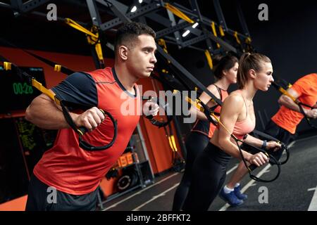 Style de vie sportif. Les jeunes faisant l'horloge presse TRX exercice à la salle de gym motivé Banque D'Images