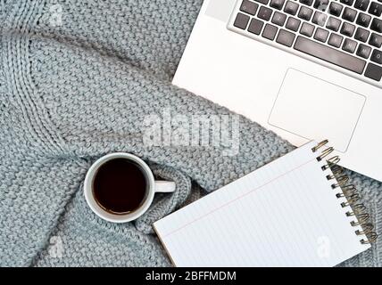 Un espace de travail confortable avec café chaud, ordinateur portable et accessoires d'écriture. Travail à la maison. Écriture. Concept chaud par temps froid Banque D'Images