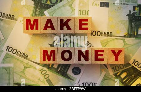 Faire des mots d'argent sur des blocs de bois mis sur des factures de 100 euros. Faire des bénéfices un concept commercial réussi Banque D'Images