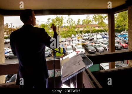 Un ministre à un service de location à Pâques dans un parc de bureaux de Santa Ana, Californie, parle d'un balcon de deuxième étage à un parking plein de fidèles dans leur voiture. Le service de drive-in a été provoqué par l'éclosion de coronavirus ou COVID-19 Banque D'Images