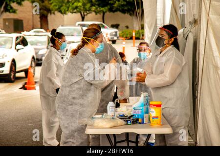 Portant des masques de sécurité, des gants en caoutchouc et des combinaisons de hazmat, les infirmières se préparent à recueillir des échantillons de diagnostic auprès des patients lors d'un trajet dans un centre de test sanguin situé dans un centre commercial Westminster, CA, pour Coronavirus ou COVID-19. Banque D'Images