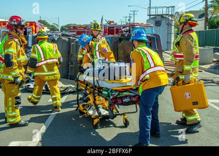 Lors d'une démonstration de sauvetage intensif, les pompiers utilisent un purney pour retirer un Manneqin d'une voiture renversée dans un parking de la caserne de pompiers à Costa Mesa, Californie. Noter le kit de premiers soins. Banque D'Images