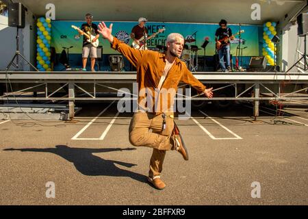 Un artiste de rue danse spontanément à la musique d'un groupe qui se produit à un festival en plein air à Huntington Beach, CA. Banque D'Images