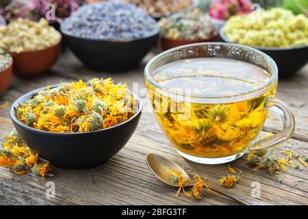 Tasse de thé marigold sain et de fleurs de calendula dans un bol. Herbes médicinales - lavande, marigold, rose, daisies, Helichrysum sur fond. medi aux herbes Banque D'Images