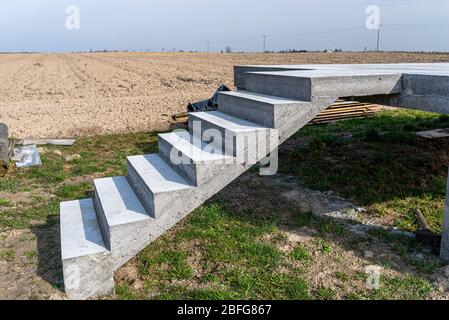 Structure rectangulaire en béton sur des poteaux en béton avec escaliers en état brut, debout dans un champ à la campagne. Banque D'Images