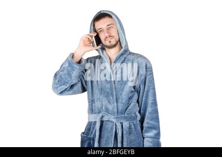 Portrait de jeune homme caucasien barbu dans un peignoir bleu parle sur smartphone isolé sur fond blanc. Concept de conversation téléphonique Banque D'Images