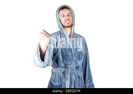 Portrait de jeune homme caucasien barbu dans un peignoir bleu frappe avec un porte-fusée en laiton dans sa main sur fond blanc. Agrésion et violence familiale conc Banque D'Images