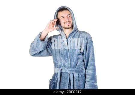 Portrait de jeune homme caucasien barbu dans un peignoir bleu parle sur smartphone isolé sur fond blanc. Concept de conversation téléphonique Banque D'Images