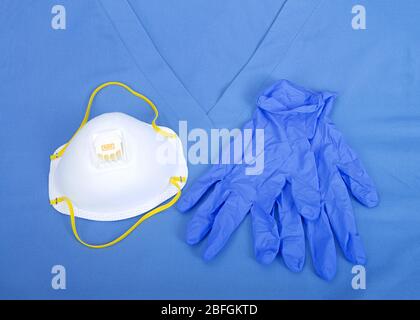 Vue du dessus, couche plate d'un masque de qualité médicale N 95 avec gants en latex bleu portant sur un uniforme de nettoyage supérieur Banque D'Images