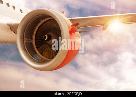 Avion avec moteur rouge en vol à travers le coucher du soleil ou le lever du soleil nuages avec lumière de l'objectif et espace de copie. Concept de l'industrie aérospatiale et de l'aviation. Banque D'Images