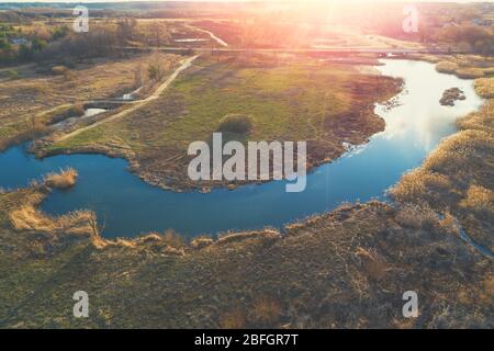 Vue aérienne sur la campagne au coucher du soleil. Rivière sinueuse sur la prairie en soirée. Beau paysage rural de la nature le soir. Banque D'Images