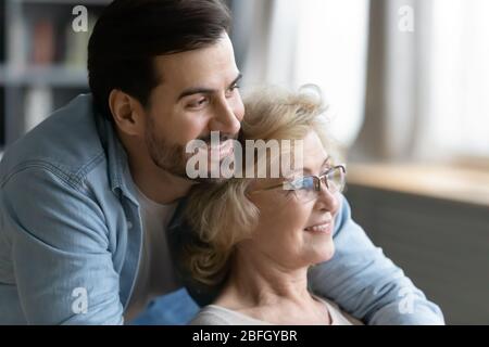 Mère âgée assise à l'intérieur alors que son fils grogner la hople Banque D'Images