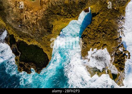 Vue aérienne sur les vagues spectaculaires de l'océan depuis une mer tropicale bleue qui s'écrasera sur un littoral rocheux Banque D'Images