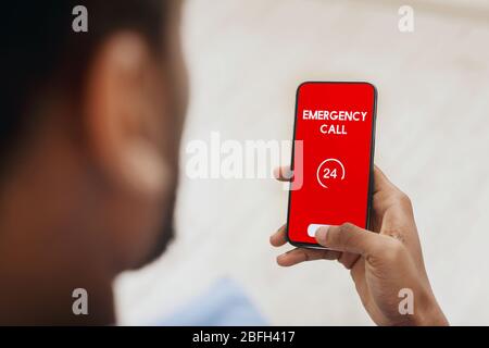 Homme noir tenant le smartphone avec le numéro d'urgence Banque D'Images