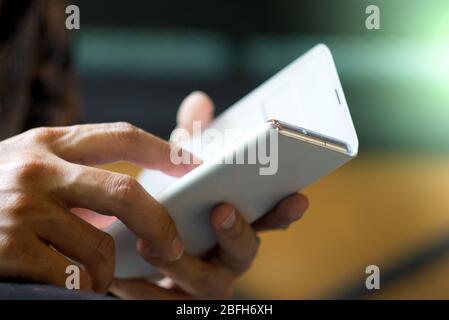 Main de mise au point de jeune homme asiatique touchant smartphone, jeune homme utilise smartphone pour discuter et surfer sur Internet. Banque D'Images