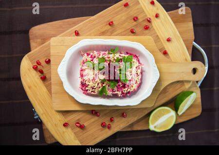 Betterave avec ail et mayonnaise. Salade panaméenne faite de pommes de terre, betteraves, œufs, oignons et mayonnaise . planche en bois Banque D'Images