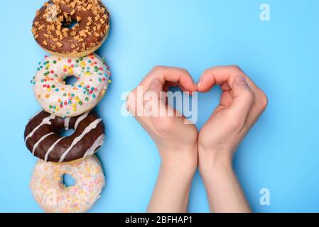 J'aime manger des beignets concept. Plat poser dessus vue en hauteur photo de quatre objets alimentaires couchés et personne enfant enfant faisant le coeur avec les mains isolat Banque D'Images