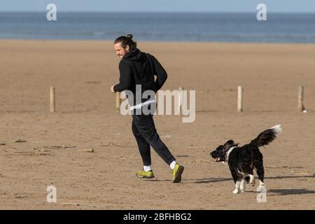 Southport, Merseyside. Météo britannique. 19 avril 2020. Une autre journée ensoleillée d'avril au printemps dans la station balnéaire, alors que les habitants de la région font de l'exercice léger sur les vastes sables côtiers de la plage nord-ouest d'Ainsdale. Le ministre Michael Gove a déclaré qu'il était trop tôt pour lever les restrictions sur les mouvements de personnes et les règles de distanciation sociale, il faut continuer à s'appliquer pendant un certain temps. Crédit: MediaWorldImages/AlamyLiveNews Banque D'Images