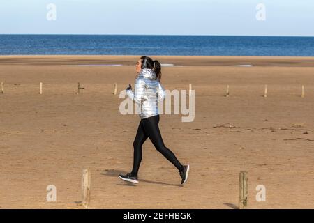 Southport, Merseyside. Météo britannique. 19 avril 2020. Une autre journée ensoleillée d'avril au printemps dans la station balnéaire, alors que les habitants de la région font de l'exercice léger sur les vastes sables côtiers de la plage nord-ouest d'Ainsdale. Le ministre Michael Gove a déclaré qu'il était trop tôt pour lever les restrictions sur les mouvements de personnes et les règles de distanciation sociale, il faut continuer à s'appliquer pendant un certain temps. Crédit: MediaWorldImages/AlamyLiveNews Banque D'Images