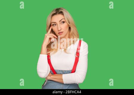 Penchons-nous ! Portrait d'une femme adulte pensive intelligente dans des combinaisons élégantes touchant le temple tout en pensant intensément, en utilisant et en méditant une solution intelligente. Banque D'Images