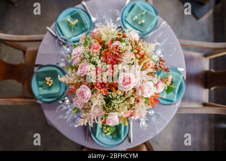 De belles fleurs disposées au milieu de la table à manger. Ce cadre ajoute une touche d'élégance et de confort à l'atmosphère de la salle à manger. Banque D'Images