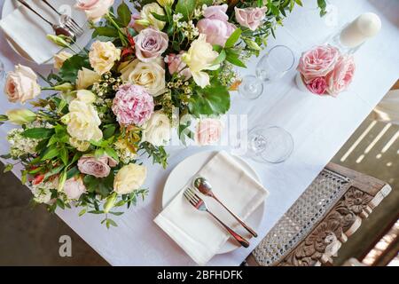 De belles fleurs disposées au milieu de la table à manger. Ce cadre ajoute une touche d'élégance et de confort à l'atmosphère de la salle à manger. Banque D'Images