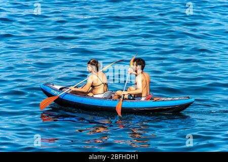 Un jeune couple, un homme et une femme pagayez dans la mer bleue sur un kayak gonflable. Golfe de la Spezia, Ligurie, Italie, Europe Banque D'Images