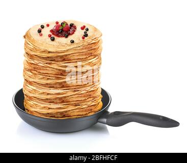 Grande pile de crêpes aux baies dans la poêle isolée sur blanc Banque D'Images