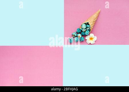Le pop-corn se déverse du cône de glace à gaufres sur fond coloré pastel. Maïs-popcorn bleu sur un cône cornucopia vue sur le dessus fond hipster lumineux. Rapide Banque D'Images