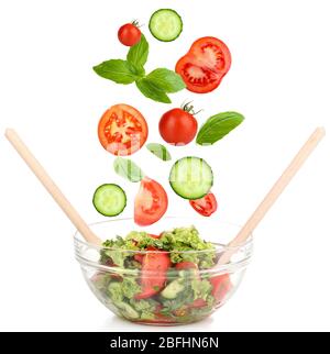 Légumes frais mélangés qui tombent dans un bol de salade isolé sur blanc