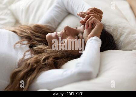 Gros plan heureuse belle femme posée au lit, en appréciant le matin Banque D'Images