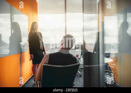 Vue depuis la porte vitrée ouverte de la réunion d'affaires dans une salle de réunion moderne de luxe située en haut d'un gratte-ciel de bureau Banque D'Images