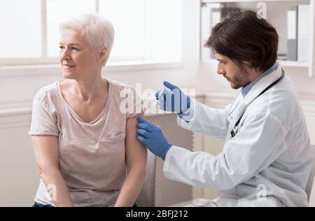 Médecin injectant le vaccin à une femme âgée à la clinique Banque D'Images