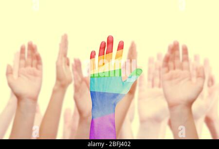 Les mains de l'homme ont peint comme le drapeau arc-en-ciel sur d'autres mains arrière-plan isolé sur blanc Banque D'Images