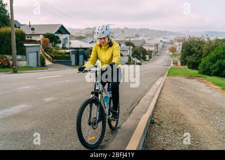 18/04/2020-femme asiatique en montée avec VTT. Une femme très fatiguée et arrêt dans la rue à Oamaru, Nouvelle-Zélande. Banque D'Images