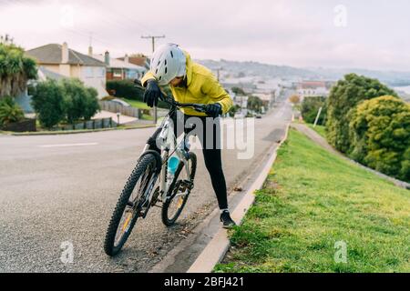 18/04/2020-femme asiatique en montée avec VTT. Une femme très fatiguée et arrêt dans la rue à Oamaru, Nouvelle-Zélande. Banque D'Images