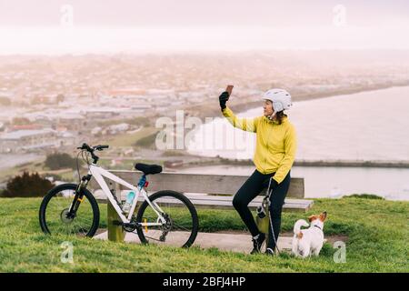 Femme asiatique en montée avec VTT. Une femme prenant une photo à l'affût avec un chien à Oamaru, Nouvelle-Zélande. Banque D'Images