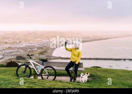 Femme asiatique en montée avec VTT. Une femme prenant une photo à l'affût avec un chien à Oamaru, Nouvelle-Zélande. Banque D'Images