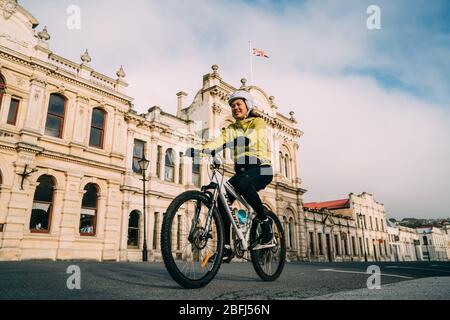 18/04/2020 une femme asiatique qui monte à vélo passe le bâtiment historique à habour Street, Oamaru, Nouvelle-Zélande. Banque D'Images