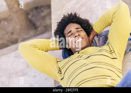Touriste noir avec cheveux afro allongé sur le sol à l'extérieur. Banque D'Images