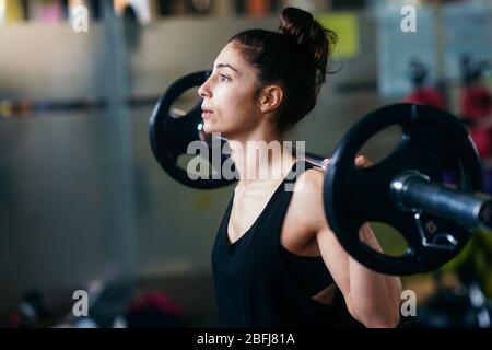 Sport femme athlétique en soulevant des poids dans la salle de sport Banque D'Images