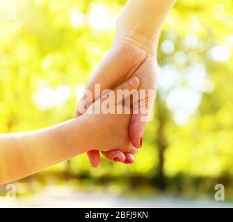 Maman et fille mains sur fond ensoleillé de nature Banque D'Images