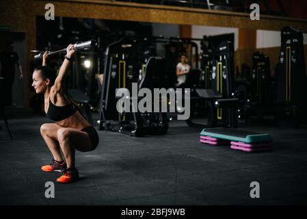 Jeune femme forte avec un corps sportif parfait soulevant vide vautour de la barbell en hauteur. Banque D'Images